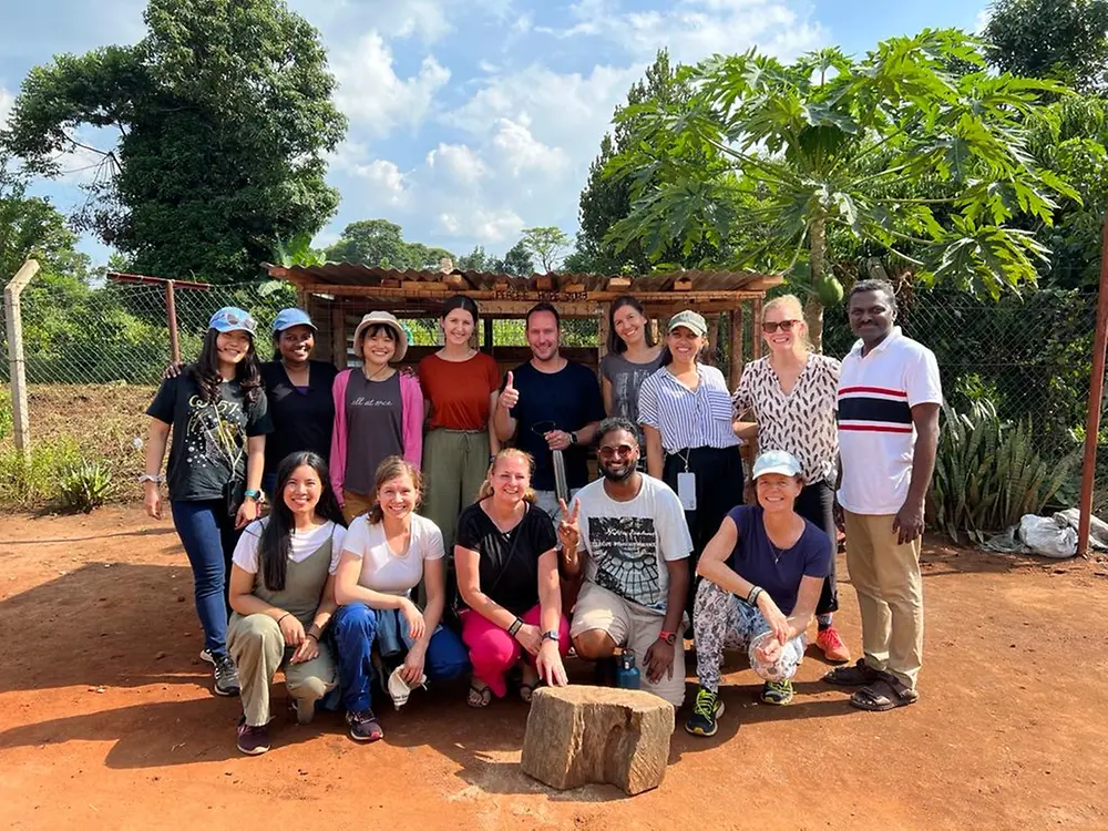 A group of people posing outdoors during a volunteering activity in Uganda.